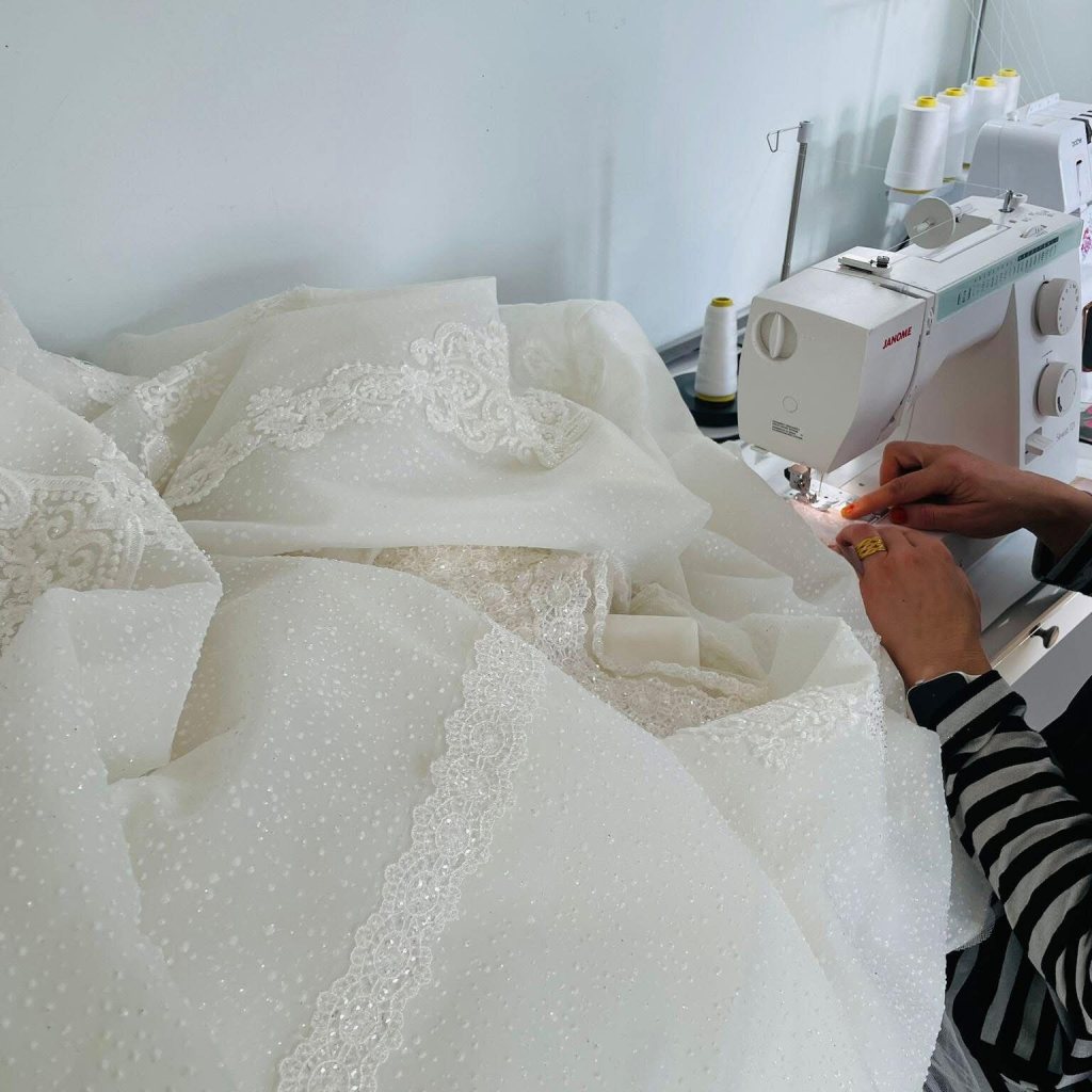 Patima working on an ivory wedding dress at the sewing machine
